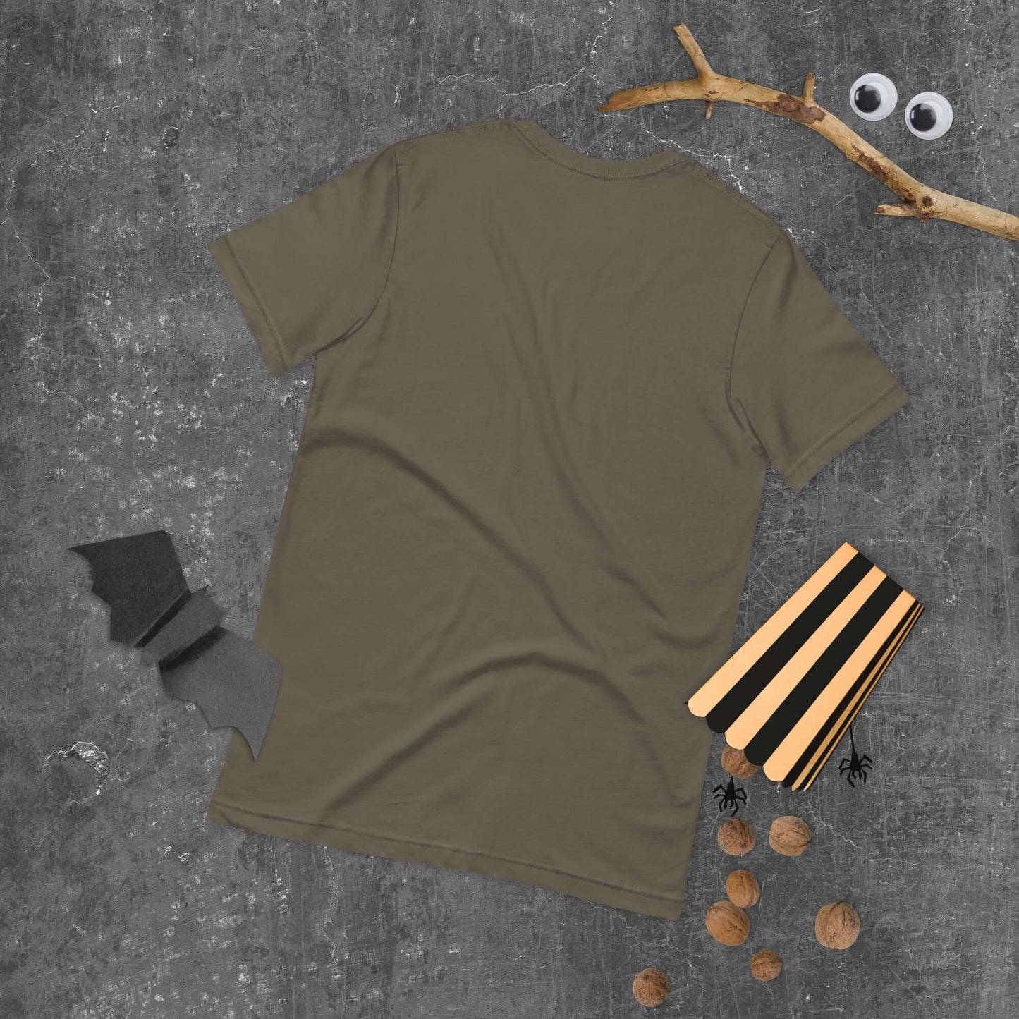 Back view of unisex t-shirt in olive green on a gray surface with Halloween decorations