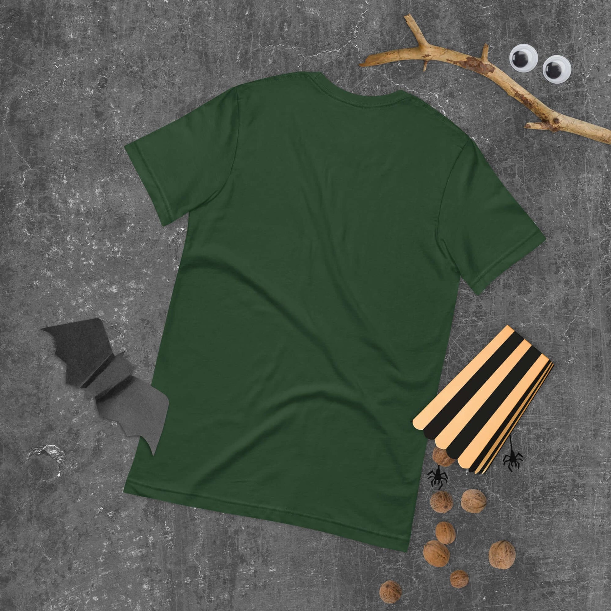 Green unisex t-shirt displayed on a dark textured background with Halloween decorations