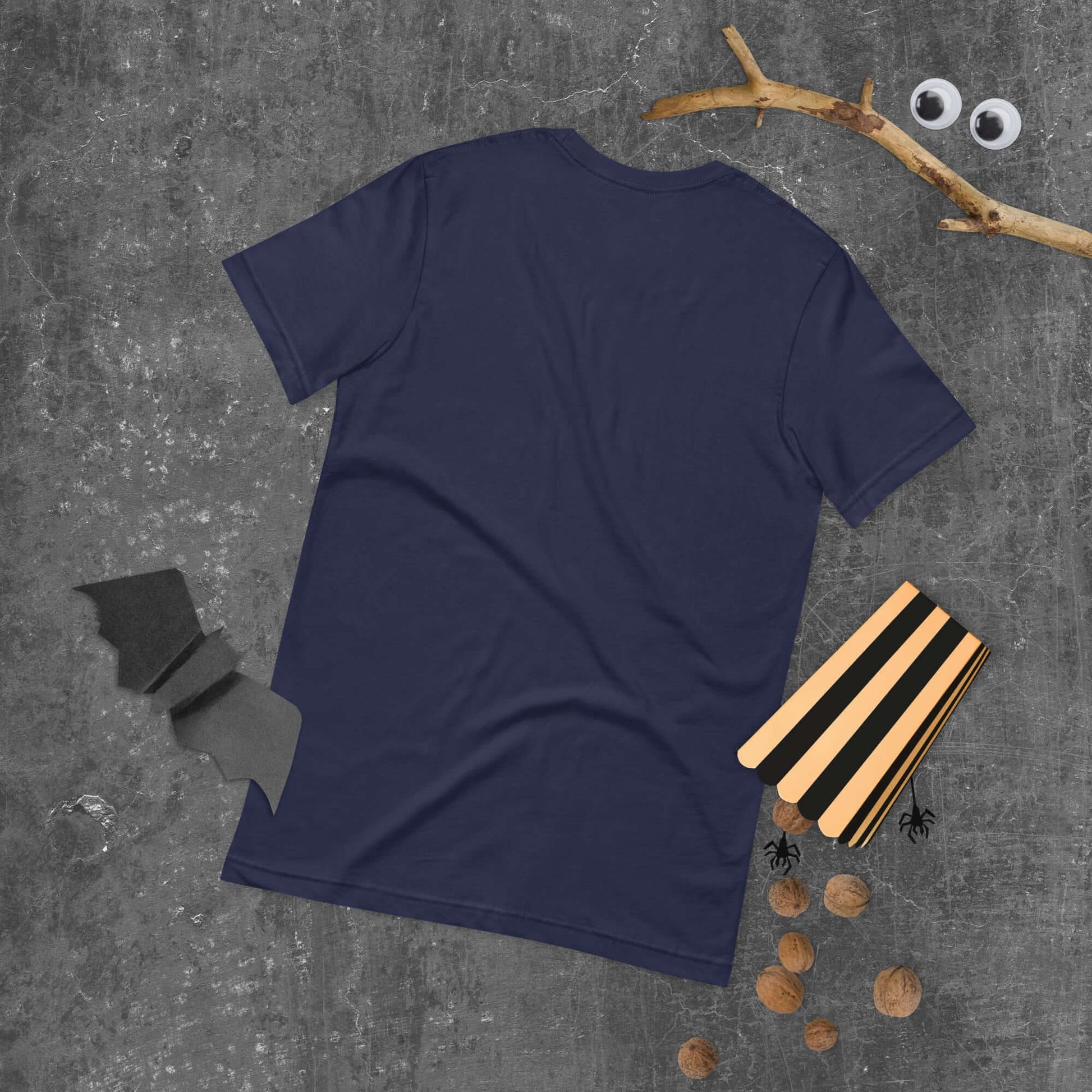 Back view of navy blue unisex t-shirt on Halloween-themed background with bat, branch, and nuts