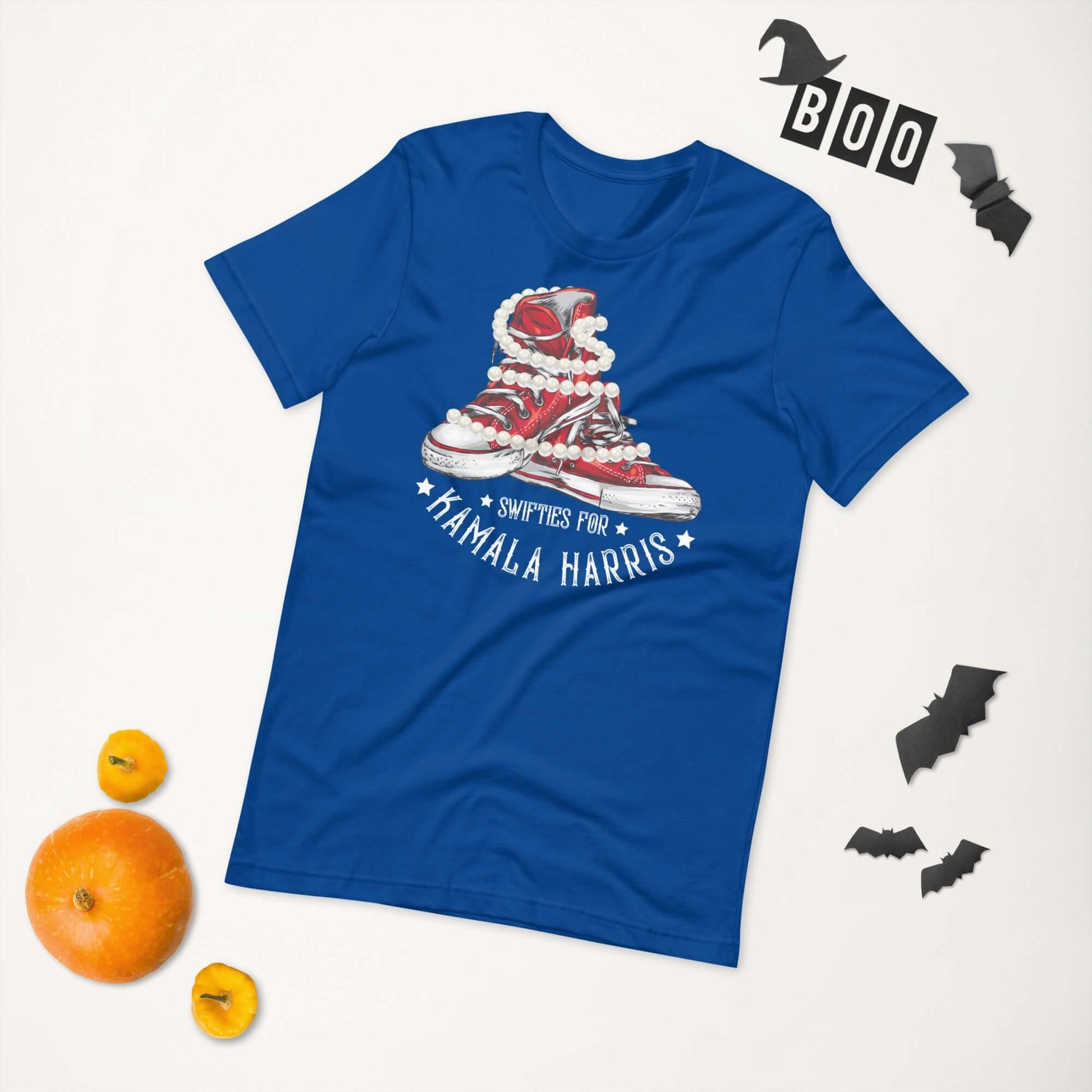 Blue unisex t-shirt with Swifties for Kamala Harris design, chucks and pearls graphic, surrounded by Halloween decor.